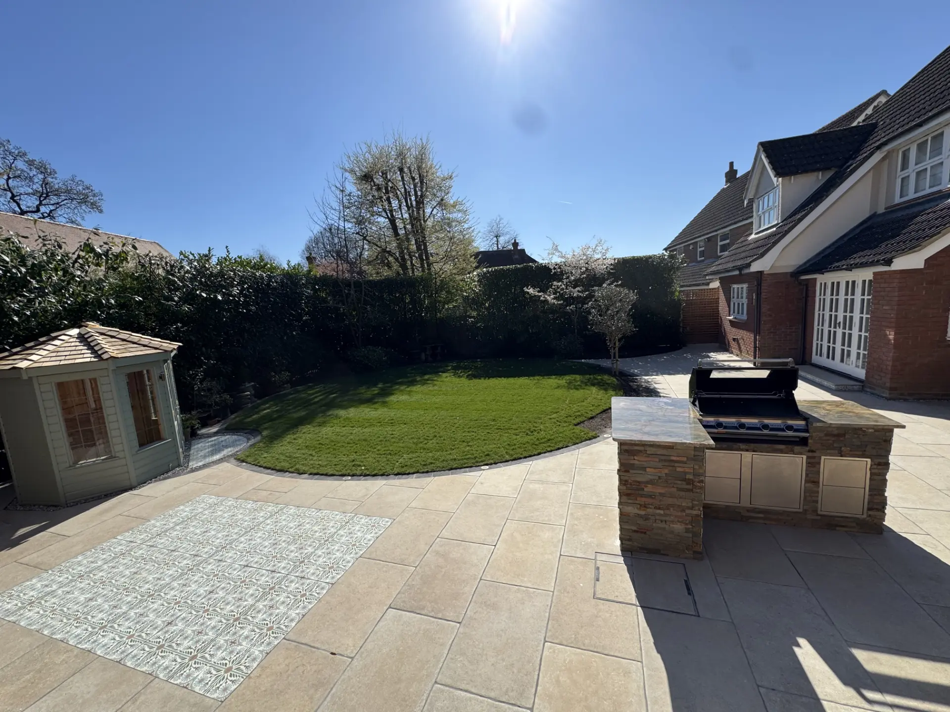 Porcelain patio with outdoor kitchen and curved lawn