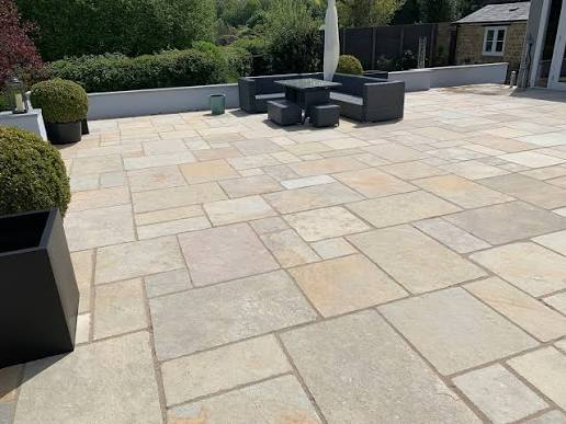 Wide riven sandstone patio with garden furniture