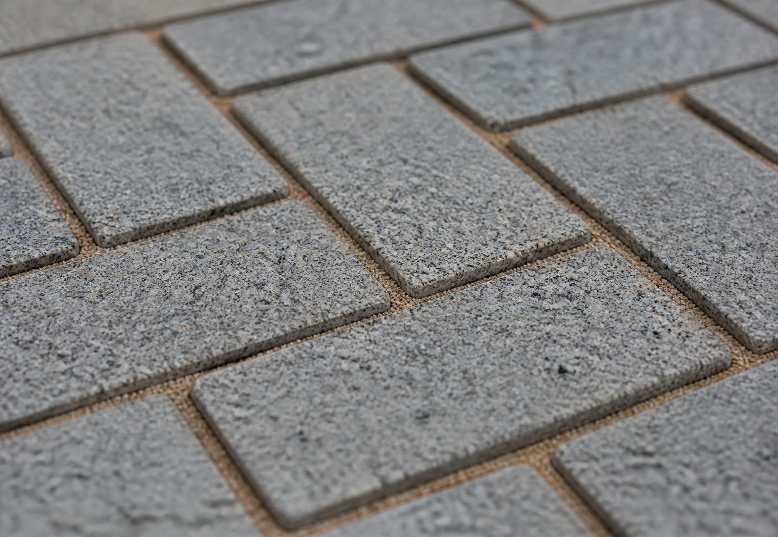 Close-up of grey granite block paving laid in a herringbone pattern
